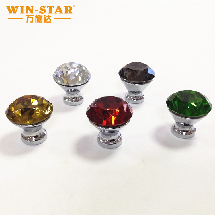 Diamond cut glass knobs reflecting light on a dark cabinet door